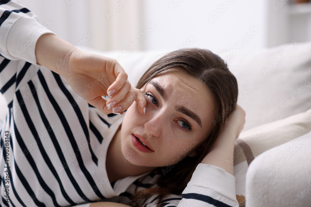 Fototapeta premium Young woman feeling fatigue and rubbing her eye at home