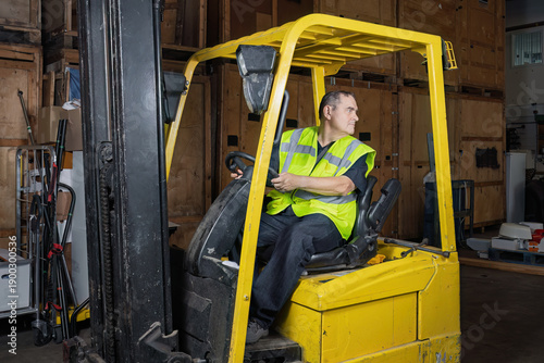 Bild auf Leinwand Warehouse worker reversing forklift truck while looking behind