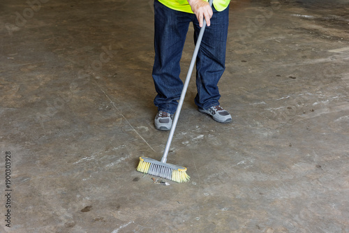 фотографія Factory Worker Sweeping Concrete Floor in Industrial Warehouse