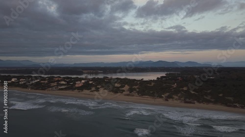 Wide aerial drone view of the coastal strip in Sabaudia, Italy, separating the lake and the Mediterranean Sea. Panoramic perspective of the sandy dunes, lake water, and mountain range
