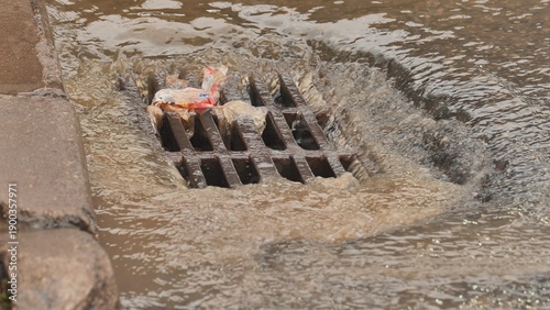 Quadro su tela Rainwater runoff carrying urban waste flowing into a clogged storm drain