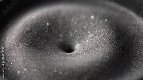 Sound waves forming ripples on a vibrating speaker surface covered in shimmering particles
