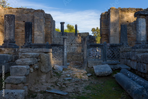 Foto Intricately carved stone columns and geometric latticework stand amid weathered brick walls and ancient masonry inside the paleochristian basilica ruins at Olympia, Greece