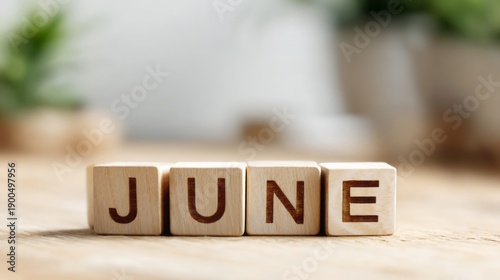 Wooden Cubes Spelling JUNE  on Natural Wooden Table with Soft White Background Minimal Style and Copy Space.
