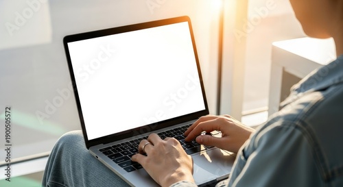 Person Typing On Laptop Computer Near Window With Bright Sunlight Shining Through During Daytime