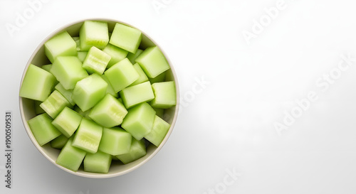 Freshly diced honeydew melon cubes in a white bowl, a vibrant green and healthy refreshing snack, presented on a clean white background
