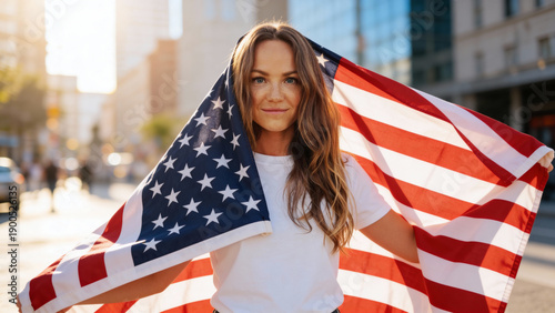 Proud serious young Afro American woman standing on street holding usa flag under blue sky looking at camera. Mixed race lady for democracy, racial equality, fair elections, changes in United States.