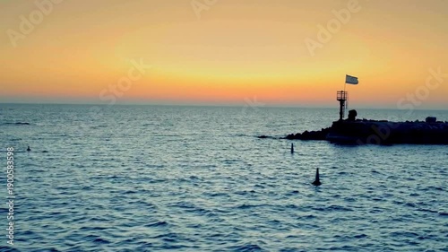 Mesmerizing view of Sunset over the Mediterranean Sea in Israel with a small jetty and the Israeli flag at twilight