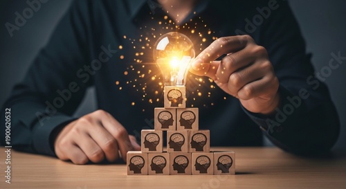 Hand Placing Glowing Light Bulb on Pyramid of Wooden Blocks with Human Brain Icons – Concept of Collective Intelligence, Creative Teamwork, and Leadership