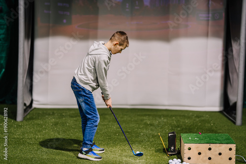 Canvastavla Young boy practicing golf swing indoors at a golf simulation area with artificia