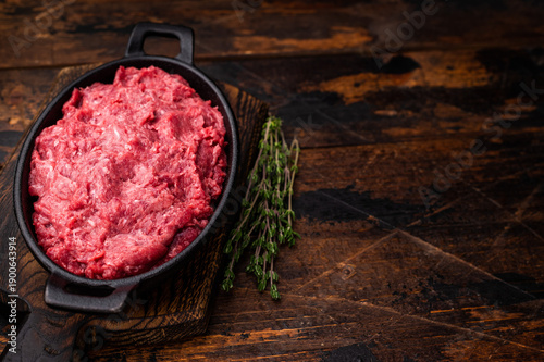 Billede på lærred Uncooked venison mince with pink pepper and fresh herbs on a wooden cutting board
