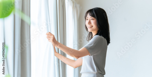 朝の光を取り入れてカーテンを開ける女性の爽やかな暮らし, Woman opening curtains to let in morning light at home Free Download 朝の光を取り入れてカーテンを開ける女性の爽やかな暮らし, Woman opening curtains to let in morning light at home - GFXLoad