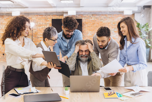 Overwhelmed senior employee experiencing burnout at work with young colleagues demanding attention and tasks, office pressure