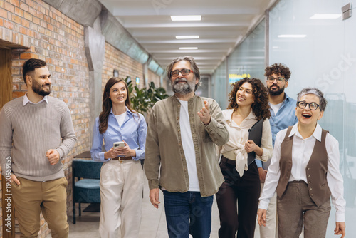 Foto Diverse business team walking and smiling through office hallway, collaborating