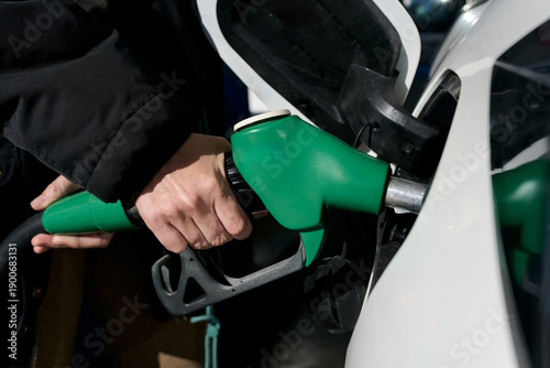 Hand using fuel pump refuelling car at gas station