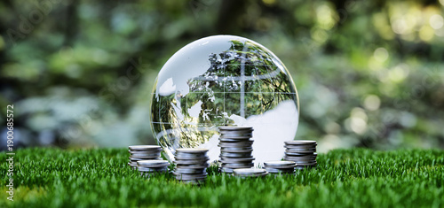 Glass globe with silver coins on green grass for ESG concept