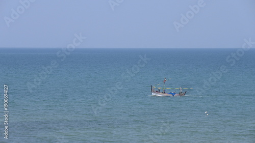 Small boat floating on calm ocean waters under clear sky.