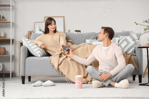 Young woman taking TV remot...