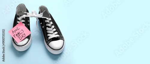 Schilderij op canvas Shoes with tied together laces and sticky note on light blue background with space for text