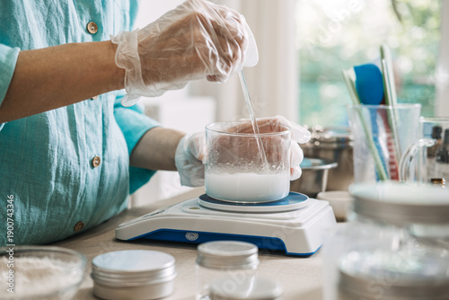 Konstfotografi Person uses glass rod to stir white liquid in glass beaker on digital scale