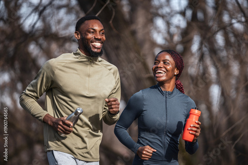 Happy black couple running together outdoors for fitness