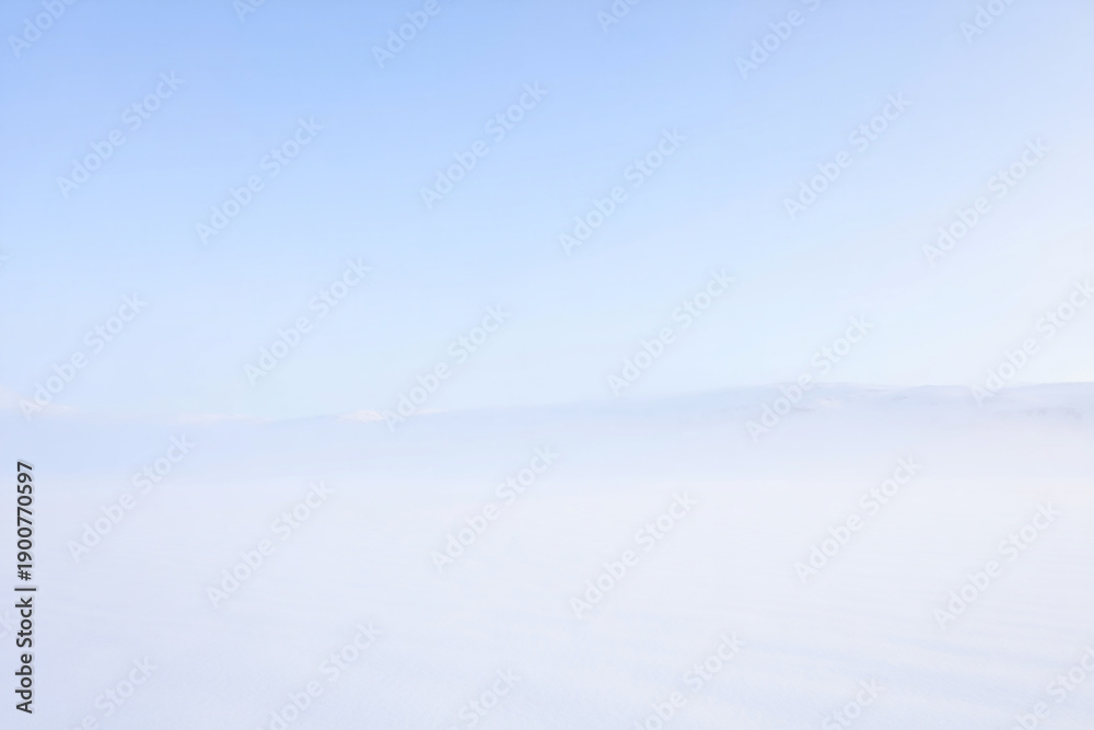 Fototapeta premium Serene landscape captured from above with fog, clouds, and a clear blue sky in a breathtaking aerial view