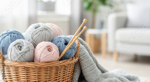 Colorful yarn balls in a wicker basket with knitting needles on a cozy blanket in a bright living room setting