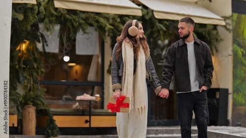 Wallpaper Mural Young couple holding hands and walking on a winter street with a gift box Torontodigital.ca