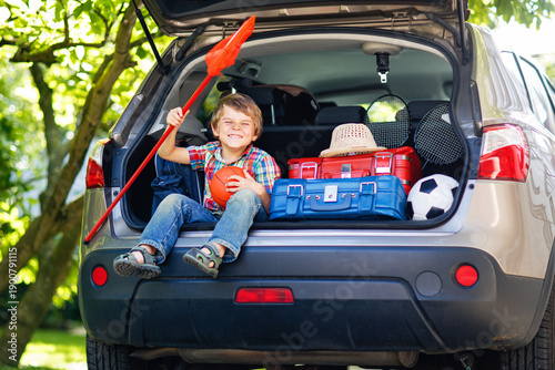 Billede på lærred Adorable little kid boy sitting in car trunk just before leaving for summer vacation with his parents