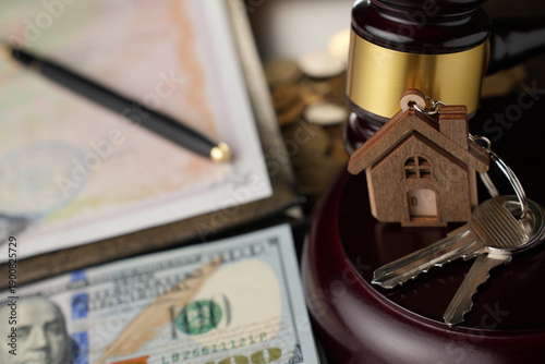Real Estate Law and Property Auction Concept. Judge's gavel, house keys, money, and legal documents on a desk. Represents foreclosure, property law, or real estate auctions