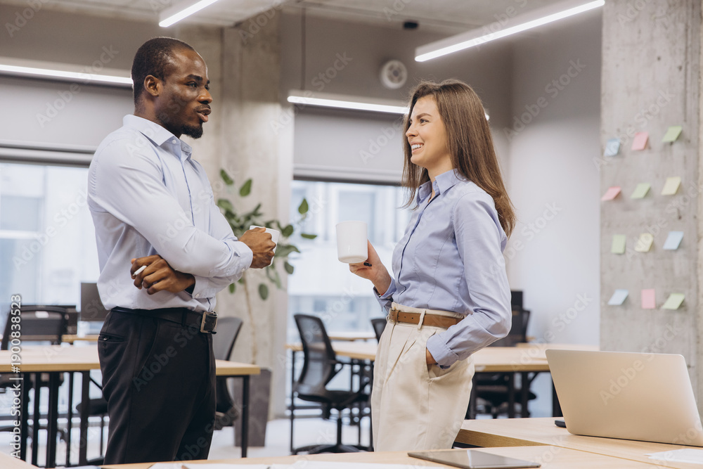 Obraz premium Diverse business colleagues networking and communicating in a modern office, enjoying a coffee break while discussing work
