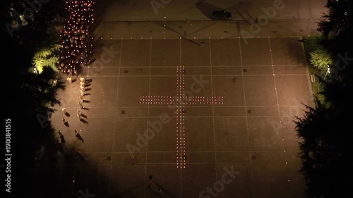 Aerial view of worshippers carrying candles around a large cross formed with lights during the Candlemas celebration at Santa Barbara Church in Italy.