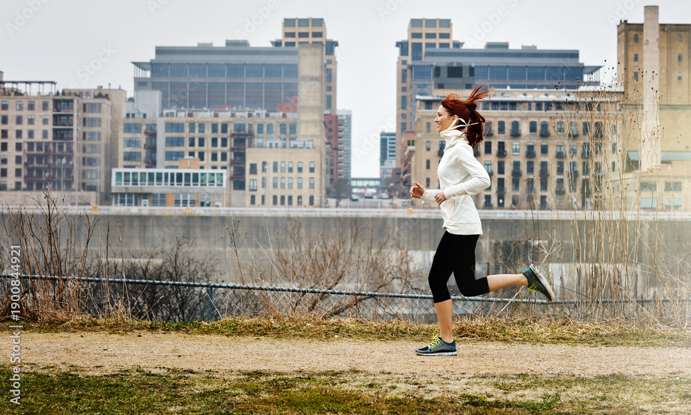 Fototapeta premium Smile, woman and running for fitness outdoor for exercise, cardio training and morning routine. Female person, runner and sprint for challenge, endurance workout and performance for wellness in city