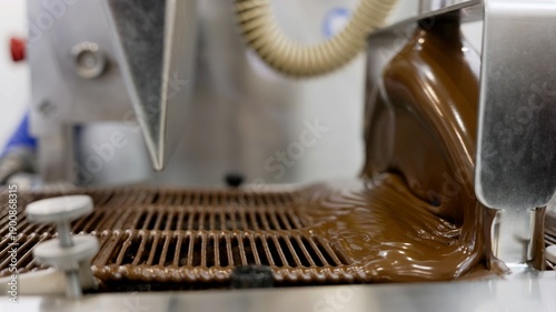 Liquid chocolate pouring on conveyor belt in factory