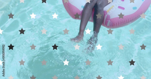 Splashing child's legs dangling in aqua pool water in swimsuit with pink donut float, star overlay