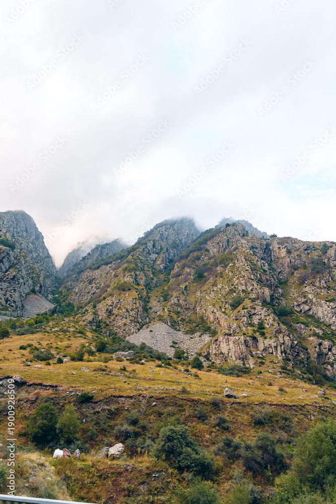 Fototapeta premium Rocky landscape with hills and clouds in the distance during sunset