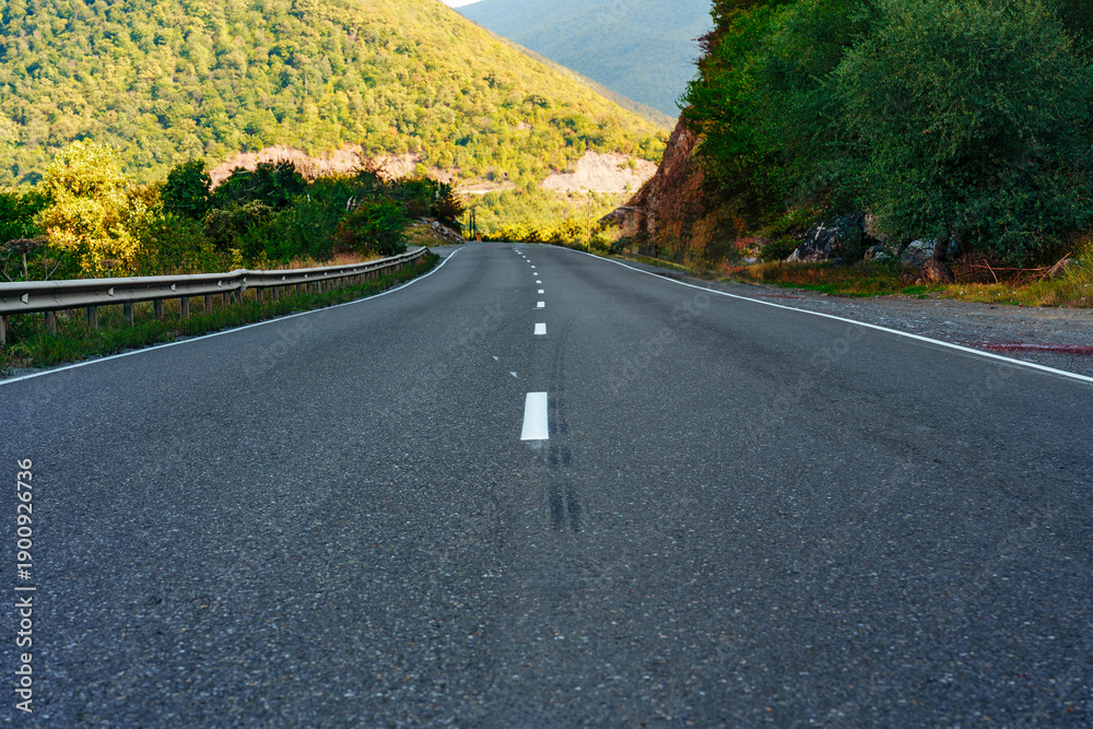 Fototapeta premium Winding road through green hills at sunset in a mountain area