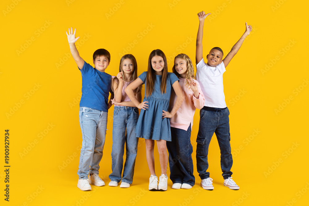 Obraz premium Confident group of preteen kids posing together on yellow studio background. Concept of teamwork, leadership, diversity, education, and positive childhood development