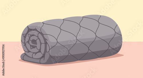 A rolled-up grey quilted blanket rests on a flat surface