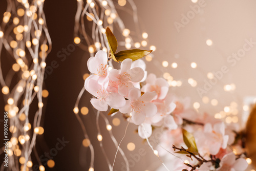 Pink blossom branch with warm fairy lights bokeh background