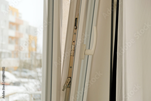 Fotografija Close-up of modern white uPVC balcony sliding door handle and latch