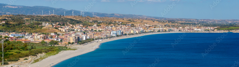 Fototapeta premium Panoramic aerial view of Catanzaro Lido, located in Calabria, Southern Italy. It is the seaside district of the Calabrian capital. It's a coastal town with colorful buildings stretching along a beach.