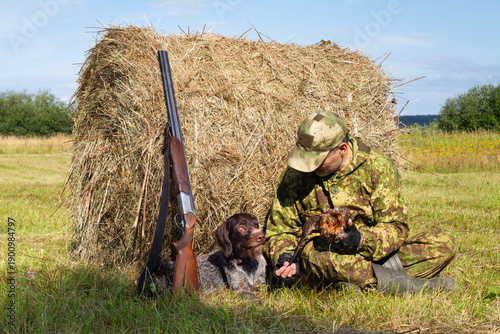 The hunter shows his dog the captured bird