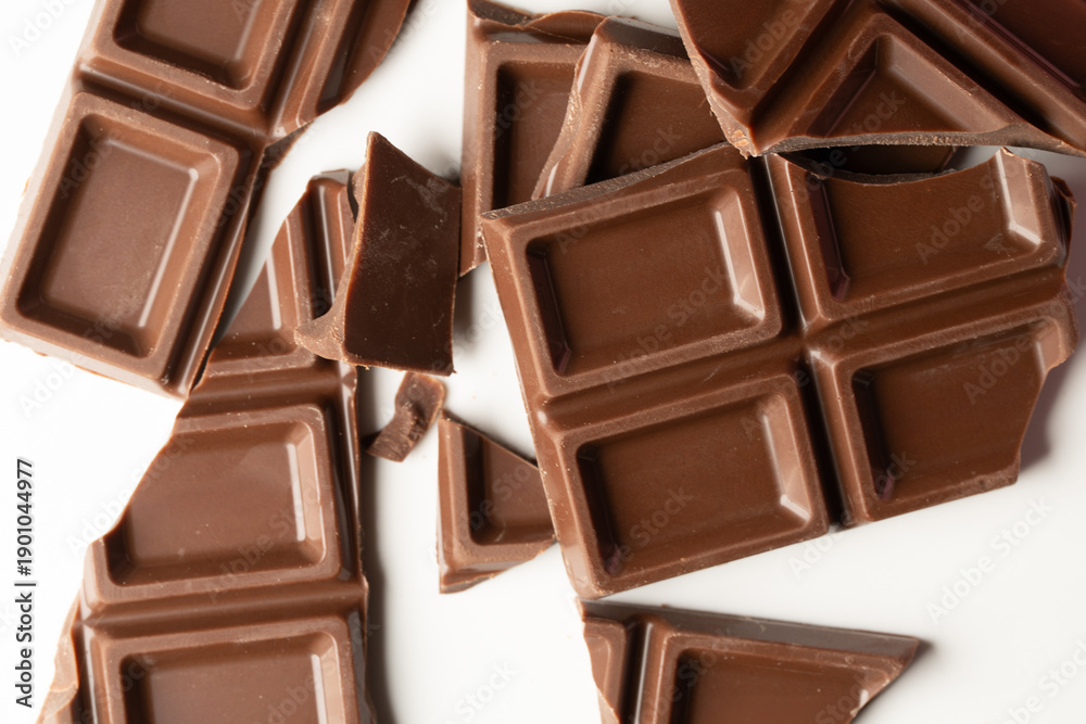 Fototapeta premium Chocolate bar broken into pieces on clean white surface
