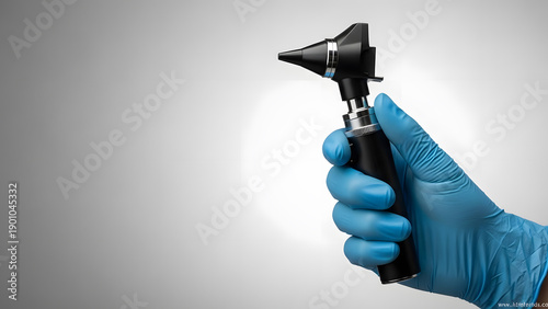 Doctor's hand holding otoscope on gray background | ENT specialist tool for ear canal inspection | Medical professional examining ear with diagnostic instrument 