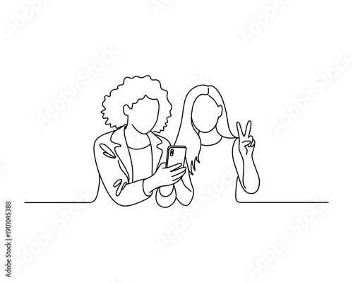 Two young women taking a selfie together with one making a peace sign gesture while looking at the phone