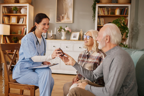 Foto A home health nurse interacts with two elderly patients in a comfortable living room
