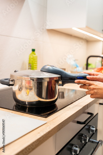 Tableau sur toile A person is cooking in a kitchen with a pressure cooker on the stove