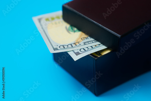 US dollars in saving box on blue background