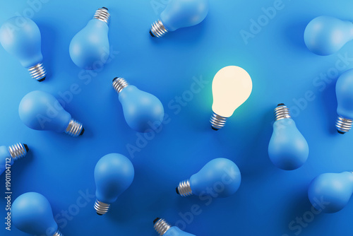 Foto Top view of many blue matte light bulbs on a blue background with one glowing bright bulb
